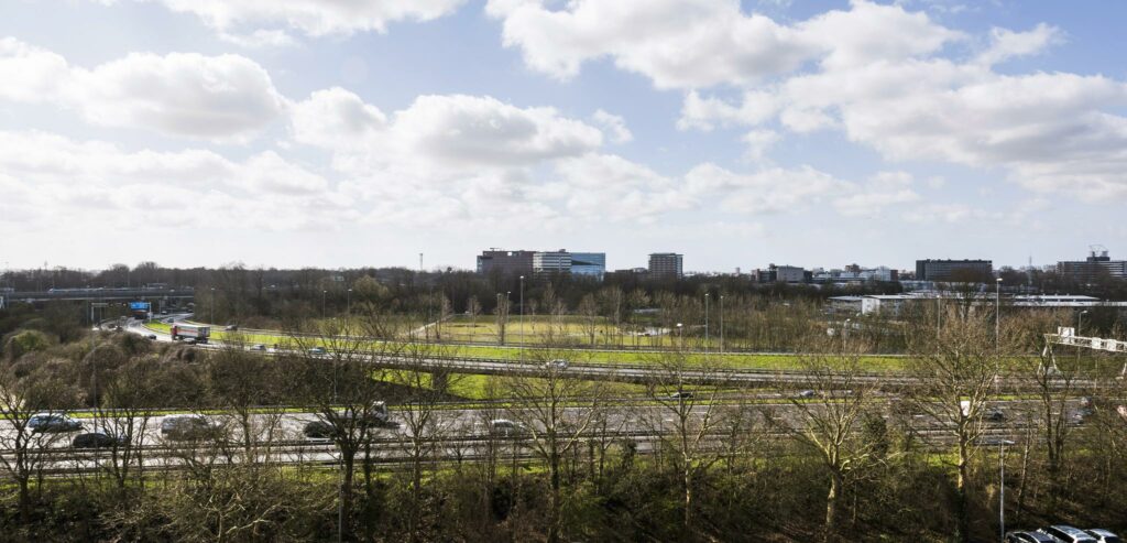 Zicht op de Anthony Fokkerweg en omliggende kantoren met op de voorgrond een drukke snelweg en kale bomen.